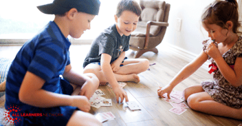 Three kids playing a card game.
