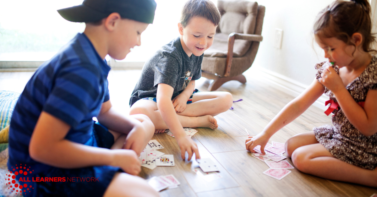 Three kids playing a card game.